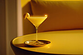 Side view of a yellow cocktail glass on a table in a luxury yellow interior. Generative AI