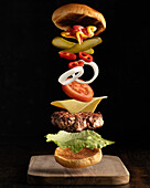 Flying ingredients of a quality meat burger isolated on a plain dark background.