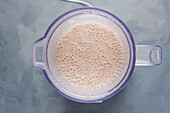 Top view of bowl of blender with mixed ingredients for milkshake