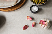 Von oben Blick auf reife Knoblauchzehen und eine kleine Schale mit Salz auf dem Küchentisch bei der Zubereitung von Speisen