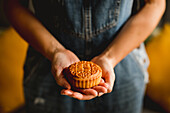 Unrecognizable female showing tradition Chinese mooncake to camera against blurred background