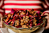 Hands of woman holding wicker bowl of chicken chilli peppers meal