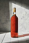Bottle of aromatic table red wine placed on wooden tabletop in studio in daylight