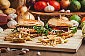 Appetizing hamburgers with vegetables and cutlets placed on wooden board with French fries in kitchen