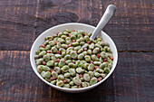 Top view of frozen broad beans in bowl served on rustic wooden table