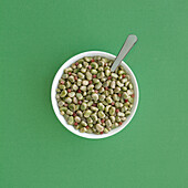Top view of frozen broad beans in bowl served on green table