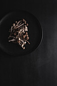 Frische Shimeji-Pilze von oben auf einem schwarzen Teller auf einem dunklen Tisch im Studio