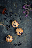 Hohe Winkel von süßen hausgemachten Muffins mit Sahne und Blaubeeren in der Nähe von Löffel Minzblatt und Blume und bereit für Dessert