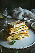 Avocado, cheese, omelet sandwich served on ceramic plate on wooden table