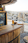Ein Glas kaltes Bier mit Snacks und Speisekarte auf einem runden Holztisch in einer Bar