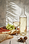 Komposition eines aromatisierten Weißweinglases, das auf einem Tisch neben einer Fleischplatte mit Weintrauben serviert wird
