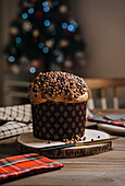 Sweet homemade baked panettone on round wooden stand near knife for celebrating Christmas