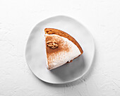 Top view of tasty carrot cake piece with walnut and cinnamon powder on icing sugar glaze on light background