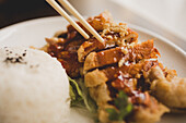 Frau sitzt in einem asiatischen Café und isst appetitlich gewürzte Ente mit Reis