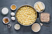 Draufsicht auf zerkleinerte Zucchini, Butter, Frischkäse, Eier, braunen Zucker, Salz, gemahlenen Zimt und Gewürze für die Zubereitung von Kuchen