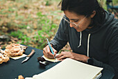 Focused female mycologist writing on paper sheet name of Boletus pinophillus mushroom