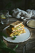 Avocado, Käse, Omelett-Sandwich auf Keramikteller auf Holztisch serviert