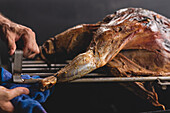 Crop faceless cook with grilling lamb on metal rack during cooking process