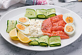 Geräucherter Lachs und Frischkäse auf einem Teller mit gekochten Eiern und Gurkenscheiben für ein schmackhaftes Mittagessen (von oben)