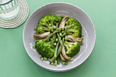 Nahaufnahme eines Gemüsegerichts mit Brokkoli, Pilzen und Erbsen von oben gesehen