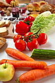 Ansicht von oben mit verschiedenen reifen Gemüsesorten und Äpfeln auf einem weißen Tisch neben anderen Lebensmitteln