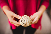 Unrecognizable female showing yummy Sheng Jian Bao to camera while standing on street