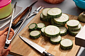 From above of sliced pieces of fresh ripe zucchini placed on wooden cutting board with knife