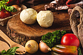 Mozzarella-Käsekugeln zwischen verschiedenen gesunden Produkten und Bio-Spateln mit Basilikumblättern auf dem Tisch
