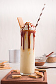 Glass with sweet caramel milkshake with vanilla ice cream and wafer cookies served on table