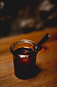 Glass of spicy chili sauce on wooden table