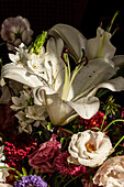 Bouquet of fresh flowers including white lilies eustoma and aster in glass vase at sunshine