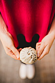 Unrecognizable female showing yummy Sheng Jian Bao to camera while standing on street