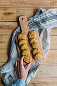 Top view of anonymous person taking yummy sweet potato falafel from cutting board over napkin and timber table in kitchen