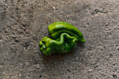 Top view close-up of two green peppers on the ground