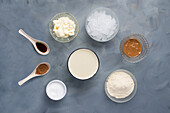 Draufsicht auf verschiedene Zutaten für die Zubereitung eines Keto-Diät-Smoothies mit gemahlenem Zimt, Vanilleextrakt und Eiscreme zusammen mit Erdnussbutter und Proteinpulver