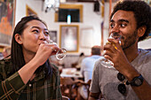 Soft focus of multiracial couple drinking beverages while having dinner together in modern restaurant during festive event