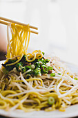 Appetizing tasty hot soya noodles on white plate with wooden chopsticks in Asian restaurant