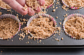From above of crop anonymous cook sprinkling dry mix on healthy coffee keto muffins in baking pan while cooking in kitchen
