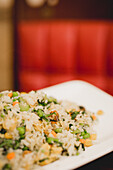 Gebratenes Gemüse, asiatisches Reisgericht vor rotem, unscharfem Hintergrund