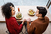 Fröhliches multiethnisches Paar isst gesundes Frühstück im Restaurant