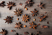 Nahaufnahme von aromatischen getrockneten Anissternen mit verstreuten Samen auf rustikalem Holztisch für Gastronomiekonzept Hintergrund