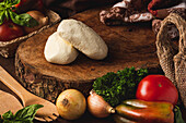 Mozzarella-Käsekugeln zwischen verschiedenen gesunden Produkten und Bio-Spateln mit Basilikumblättern auf dem Tisch