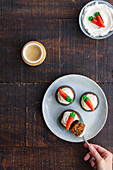 Top view of cropped unrecognizable person hand eating delicious vegetable cupcakes with small carrot sweet decoration on top placed on plate on wooden table