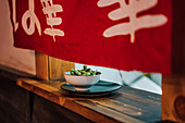 Traditional Asian dish in white ceramic bowl on wooden window in restaurant