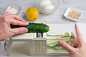 POV Schuss von crop gesichtslosen Koch Schneiden von frischen Gurken auf Scheiben auf Cutter während der Vorbereitung von Speisen am Tisch in der Küche zu Hause