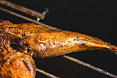 Tasty grilled suckling lamb with crispy crust placed on metal rack of modern black barbecue in light cafe during cooking process
