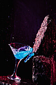 Glass of Blue Lagoon alcoholic cocktail placed on rough stone in bright studio