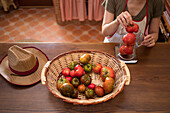 housewife weighing fresh tomatoes in glass jug on kitchen scale while cooking food at home
