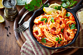 Von oben: Spaghetti mit Garnelen in Tomatensoße, garniert mit Petersilie und Zitronenspalten