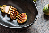Green fig slices in modern black bowl on the table with grunge texture. minimal concept food. Also known as ripe white figs